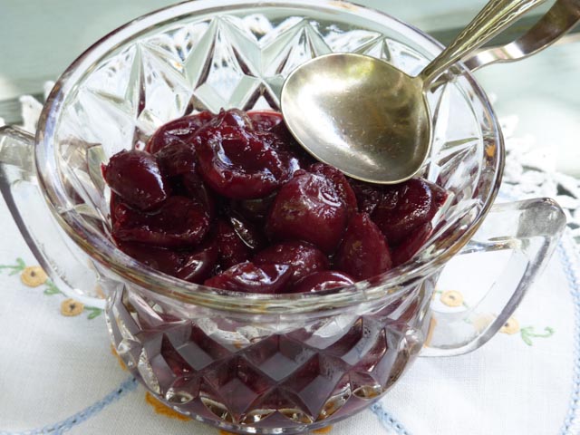 Bowl of spicy cherry sauce in with silver ladle sitting on top