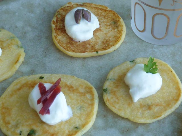 Small potato pancakes topped with sour cream and slivers of beetroot and capers