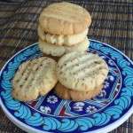 Pile of tahini cookies piled on top of a ceramic tile with reb, white and blue Middles Eastern pattern