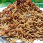 A plate is piled high with rice, lentils and crisply fried onions