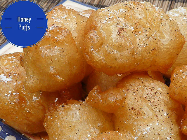 Balls of puffed dough in a honey syrup dusted with icing sugar and cinnamon