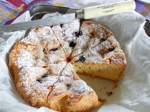 blueberry batter cake cake sliced into wedges with knife resting on top