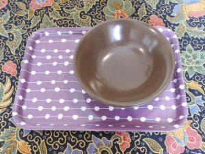two brown bowls sit on a small purple and white tray