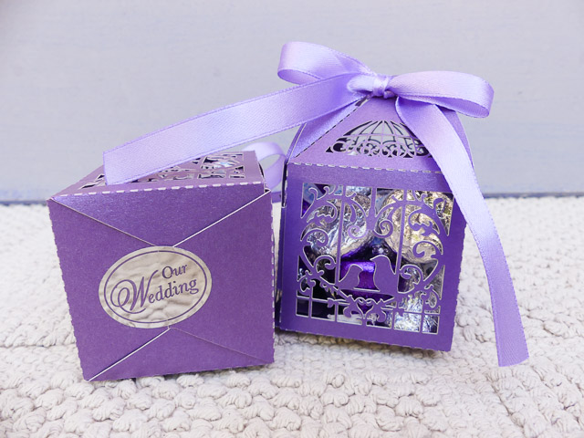 two purple cardboard boxes with cut out morifs and purple ribbons tied on top