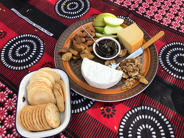 cheese plate with fruit, nuts and crackers on a bold printed table cloth