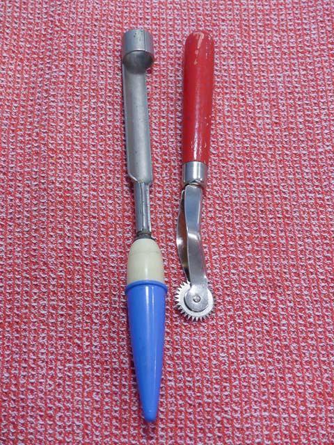 old fashioned apple corer with blue handle and pastry wheel with red handle sit on a red tea towel