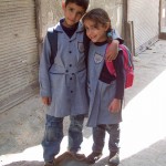 a young brother and sister in school uniform walk home for lunch in the alley ways of Damascus