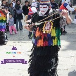 A religious festival reveller in balaclava, fringed coat and whip