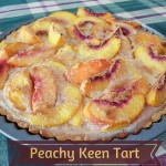 Sliced Peach Tart still in tart tin sitting on a chequered table cloth
