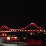 A night time view of Brisbane's Story Bridge, viewed from the CBD. The bridge is picked out in red lights.